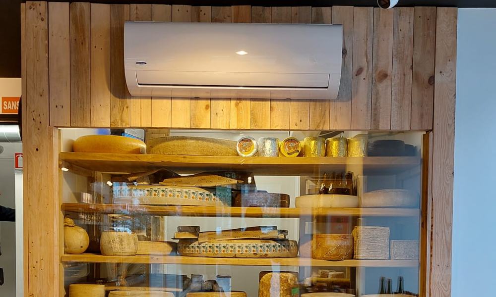 Climatiseur mural au-dessus d’une vitrine à fromages dans une fromagerie