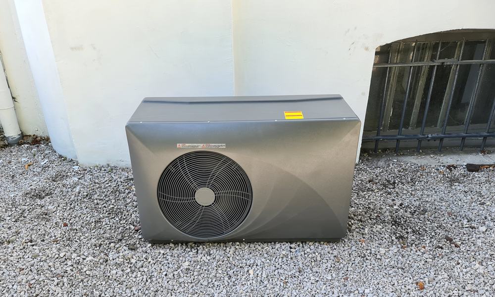 Pompe à chaleur de piscine avec grand ventilateur, posée sur gravier