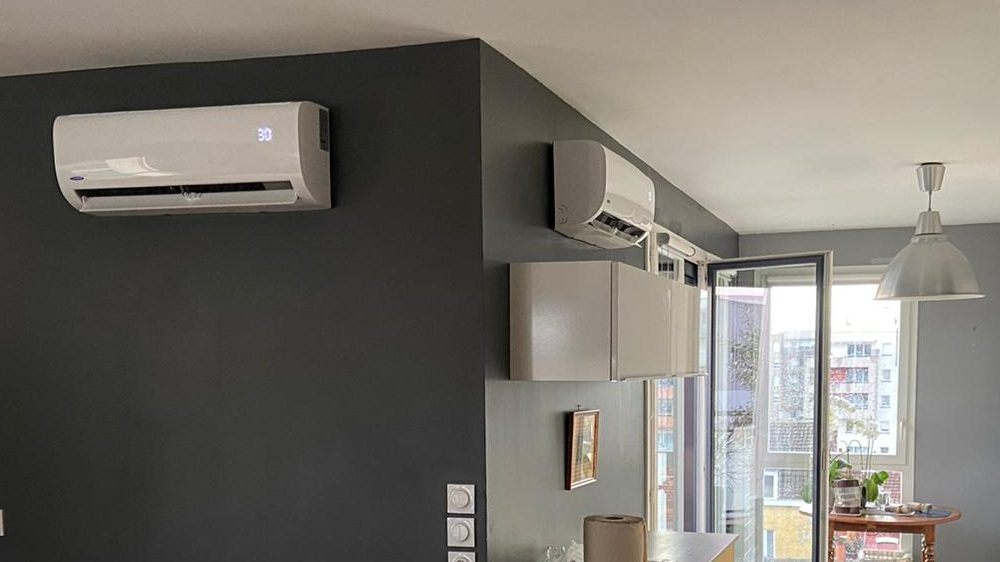 Deux climatiseurs muraux installés dans le séjour et la cuisine ouverte d’un appartement