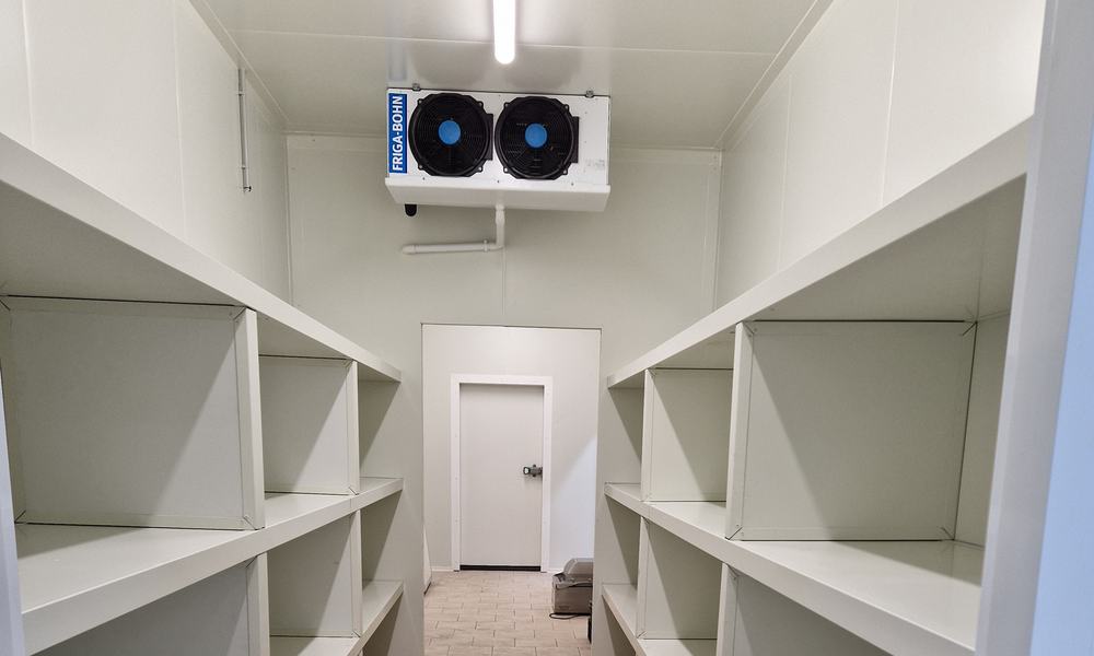Intérieur d’une chambre froide positive avec étagères blanches et évaporateur à deux ventilateurs