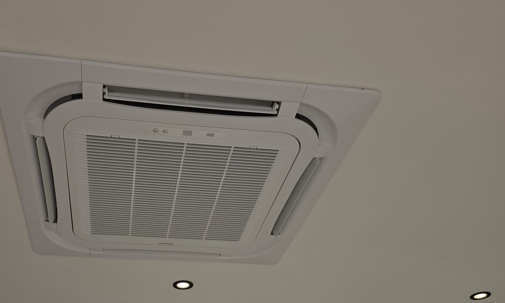 Climatiseur de type cassette encastré dans le plafond d’une pièce vitrée