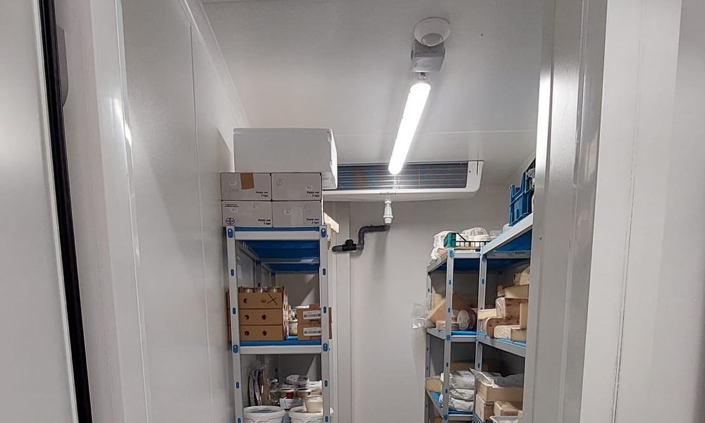 Intérieur d’une chambre froide de fromagerie avec étagères et évaporateur